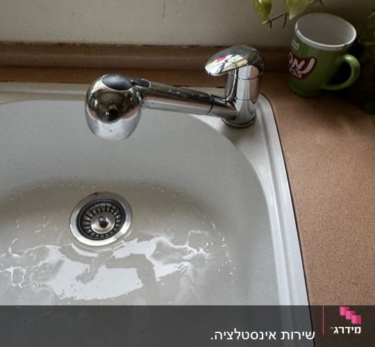 ברז וכיור במטבח עם כוס ירוקה